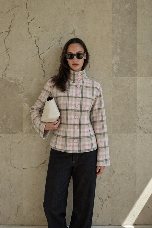 Rosalie beige and pink plaid jacket styled against a stone wall